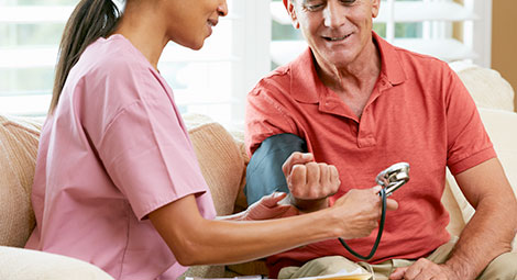 Doctor visiting patient at home. The doctor is taking the blood pressure of the patient